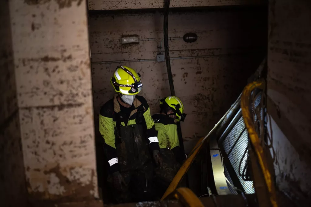 Bomberos trabajando en un garaje afectado por la DANA